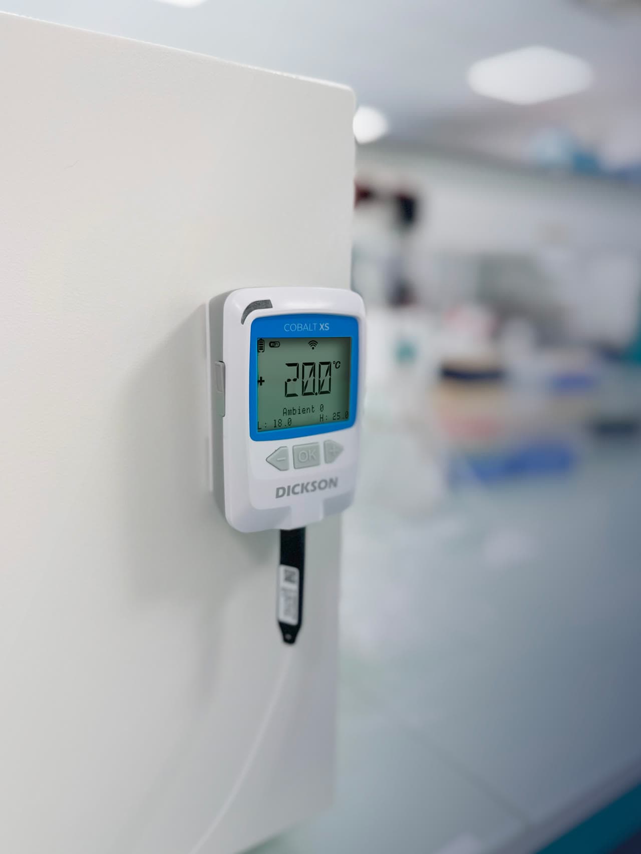 Dickson Cobalt XS Wi-Fi data logger mounted on a wall in a pharmaceutical laboratory, displaying real-time temperature reading