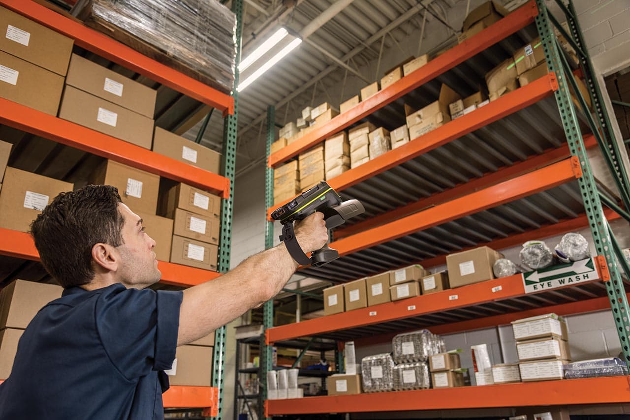 Warehouse worker using Zebra RFD90 long-range RFID sled to scan inventory on shelves